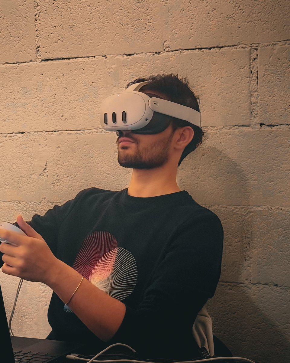 Burhan at his desk wearing a Meta Quest headset, holding the controllers.